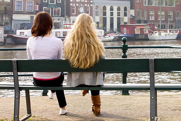 Twee vrouwen zitten overdag buiten op een bankje