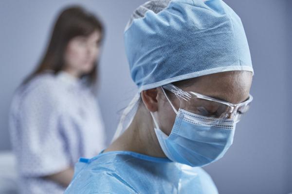 Arts staat voor patiënt die op bed zit in onderzoeksruimte