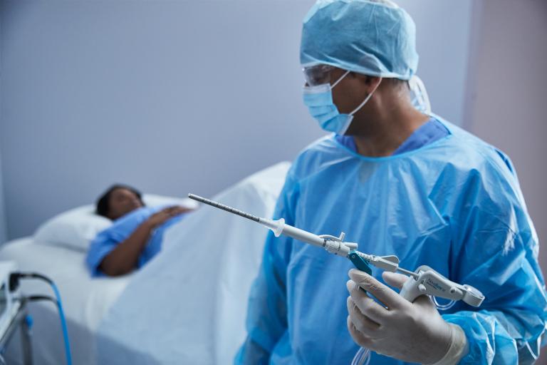 Chirurg in OK-outfit met medisch hulpmiddel, en patiënt op ziekenhuisbed