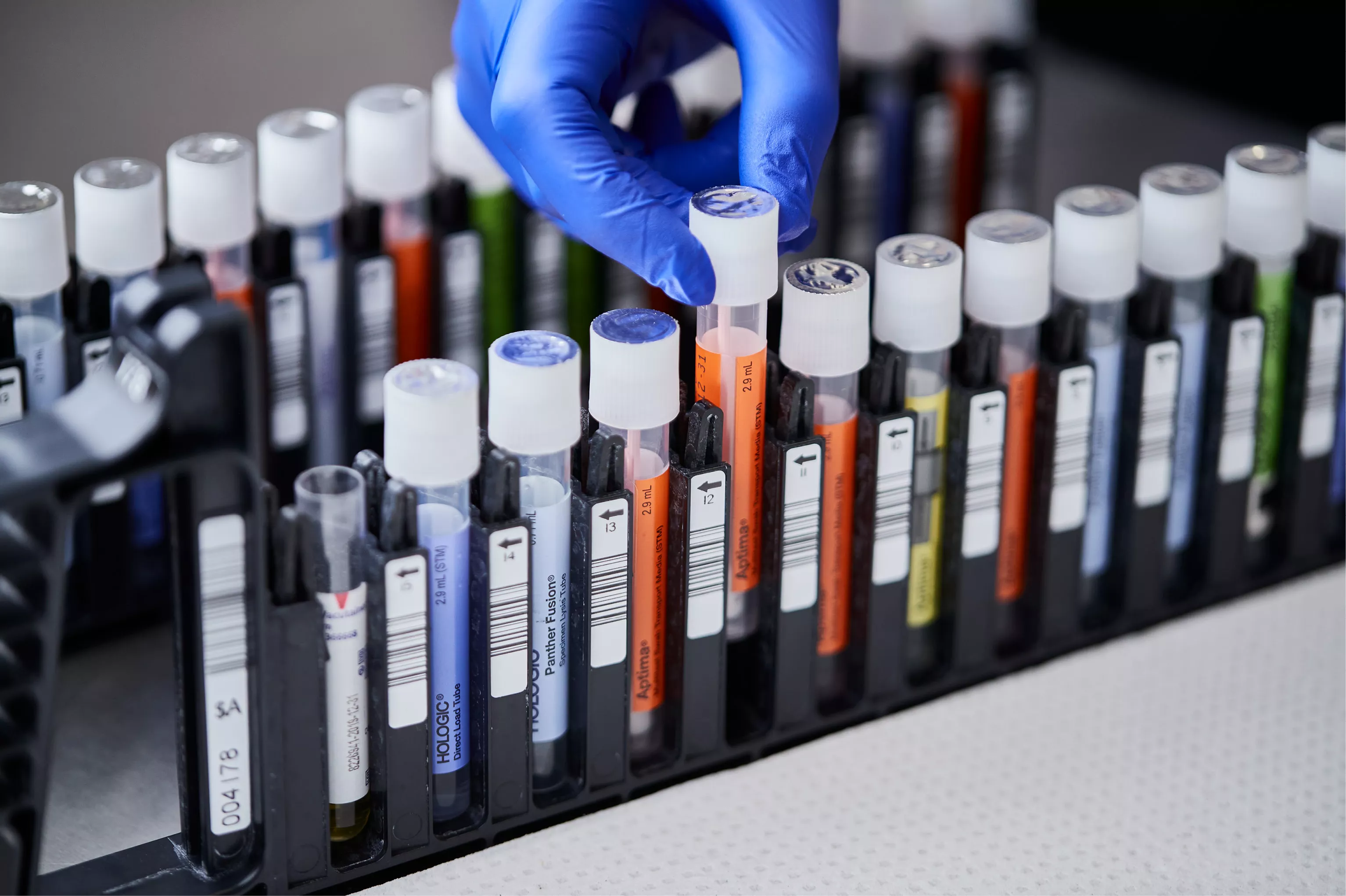 Hand met handschoen neemt flacon uit tray