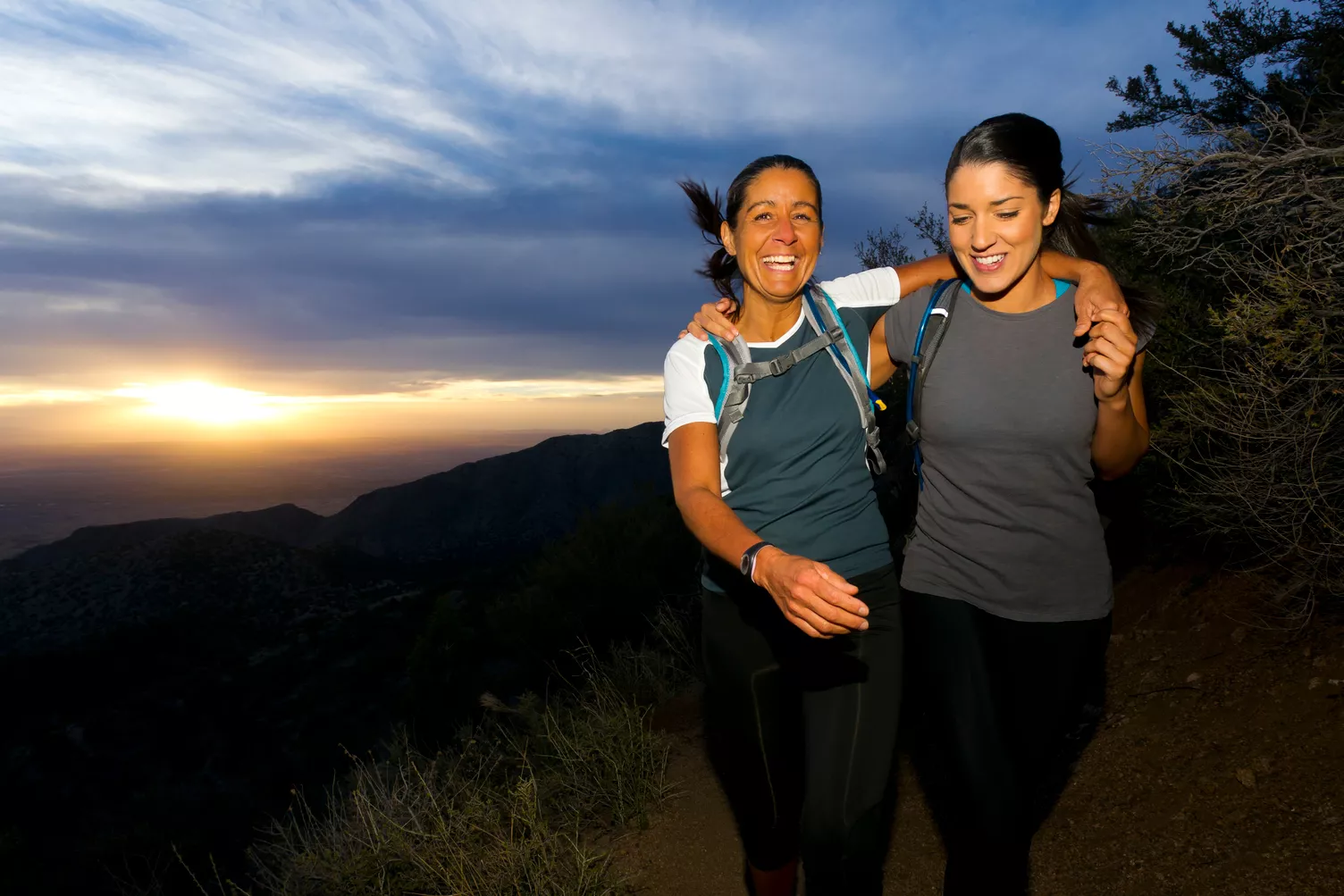 Twee vrouwen wandelen een heuvel op bij zonsondergang