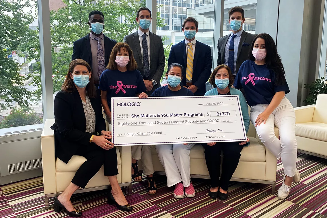 Groepsfoto van mensen met een grote promotiecheque ter ondersteuning van de programma's She Matters en You Matter